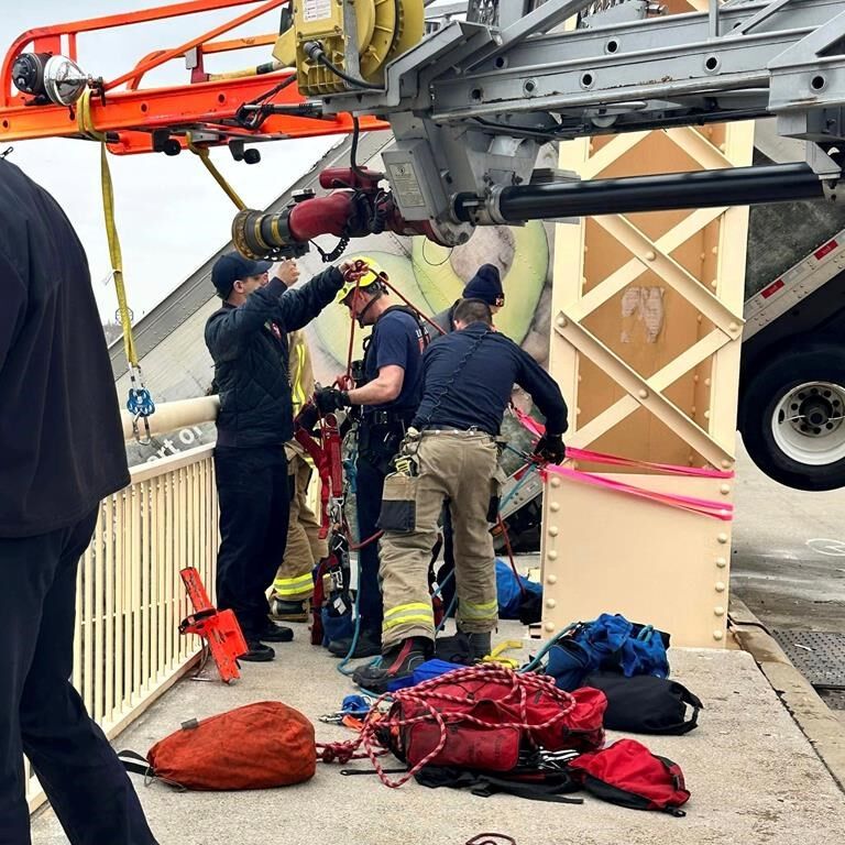 The semi driver rescued dangling from a bridge had been struck by an oncoming vehicle: mayor